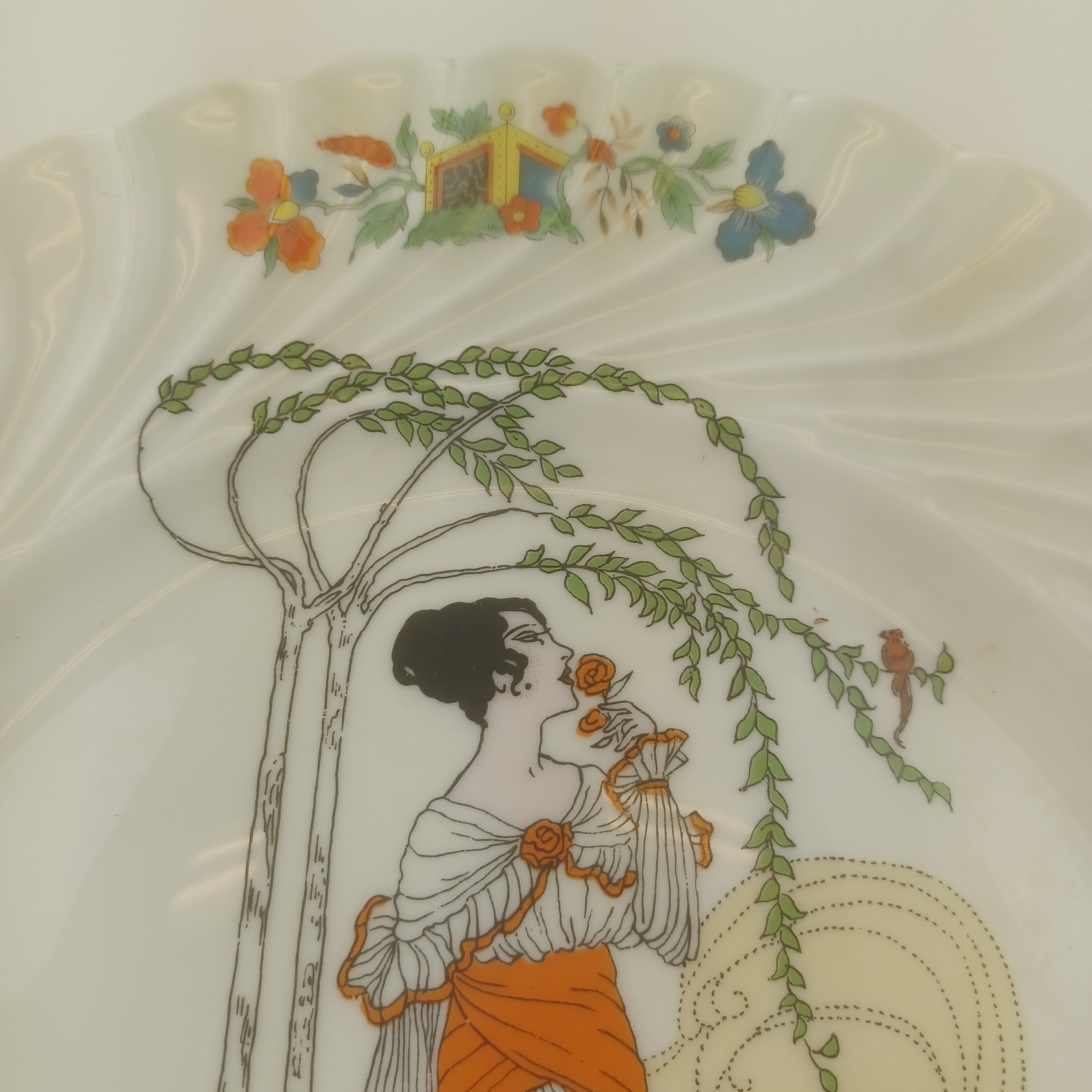 Assiette décorative de 27cm de diamètre en porcelaine d'art de Limoges, Valette, représentant une femme sentent une rose sous un arbre pris par le vent Très bon état - Vue 2 - 