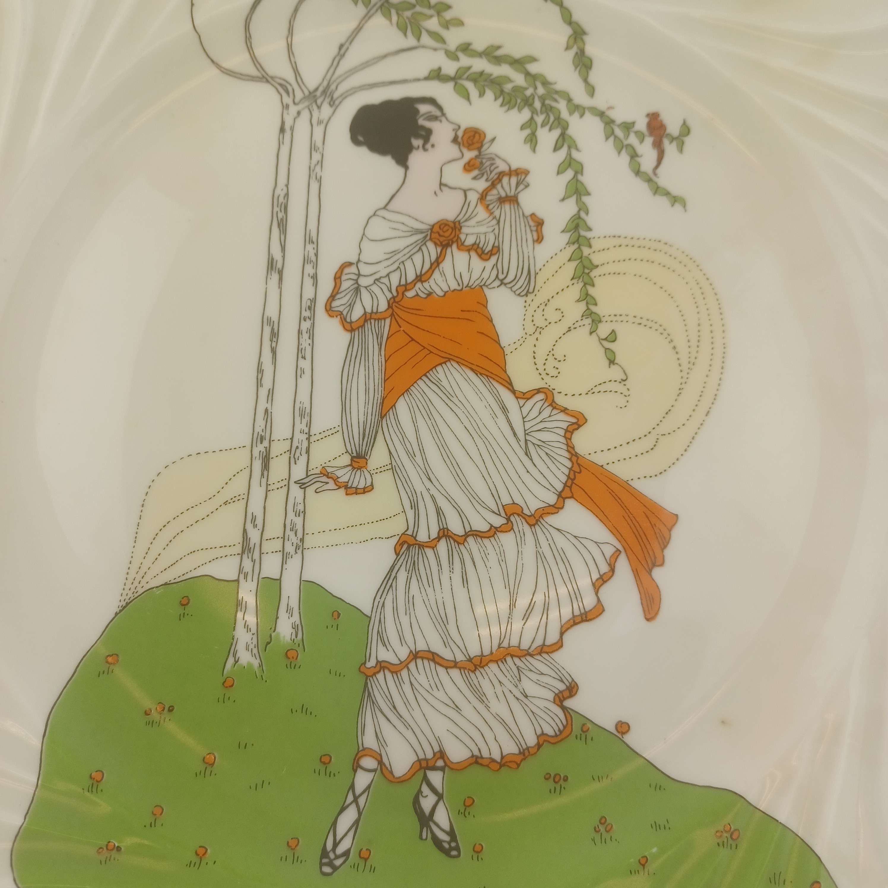 Assiette décorative de 27cm de diamètre en porcelaine d'art de Limoges, Valette, représentant une femme sentent une rose sous un arbre pris par le vent Très bon état - Vue 3 - 