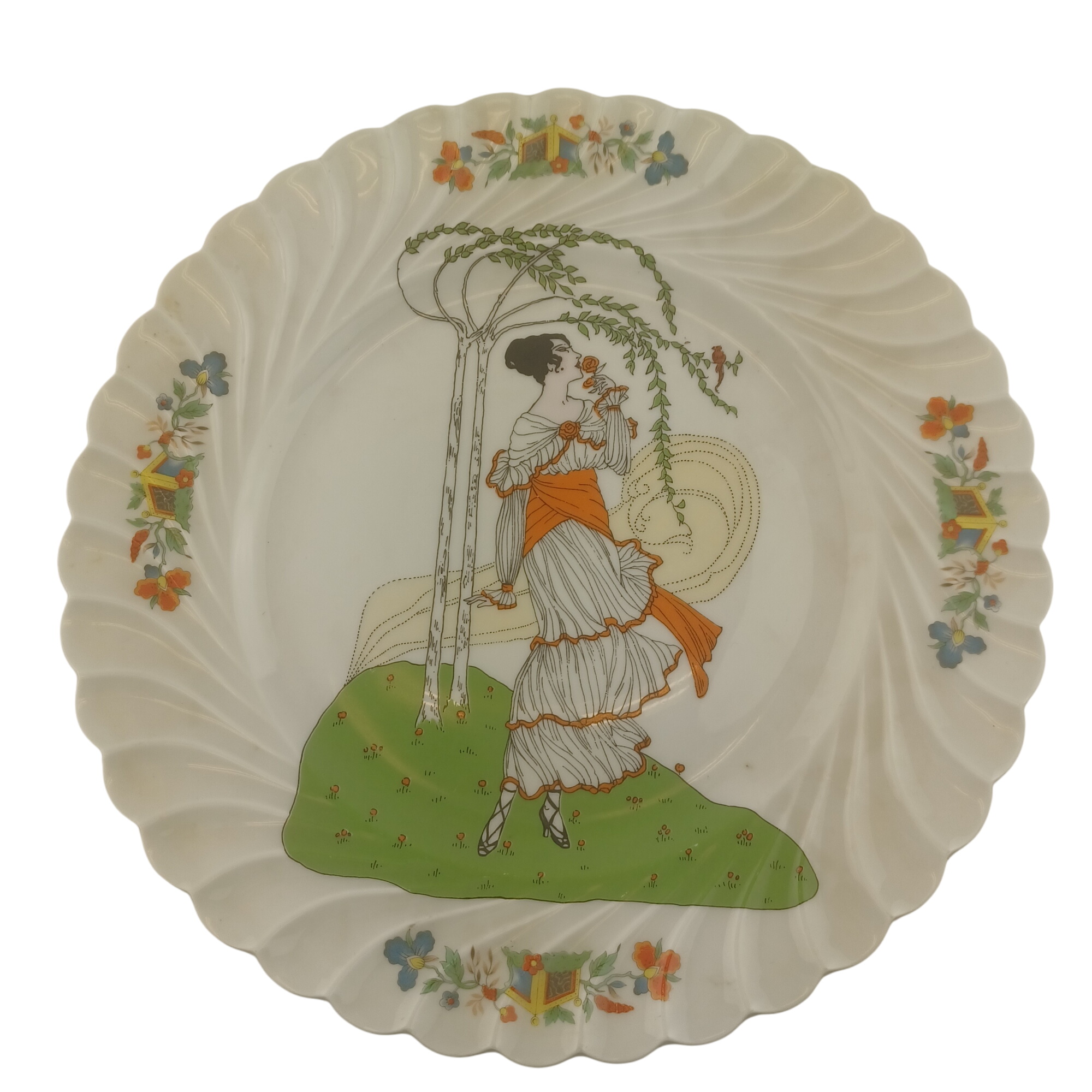 Assiette décorative de 27cm de diamètre en porcelaine d'art de Limoges, Valette, représentant une femme sentent une rose sous un arbre pris par le vent Très bon état -  reconditionné disponible sur Label Emmaüs